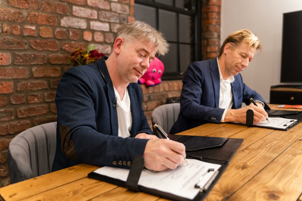 Elia's Chris Peeters and Octopus' Greg Jackson signing their contracts at an event at COP26. Image: Octopus Energy.