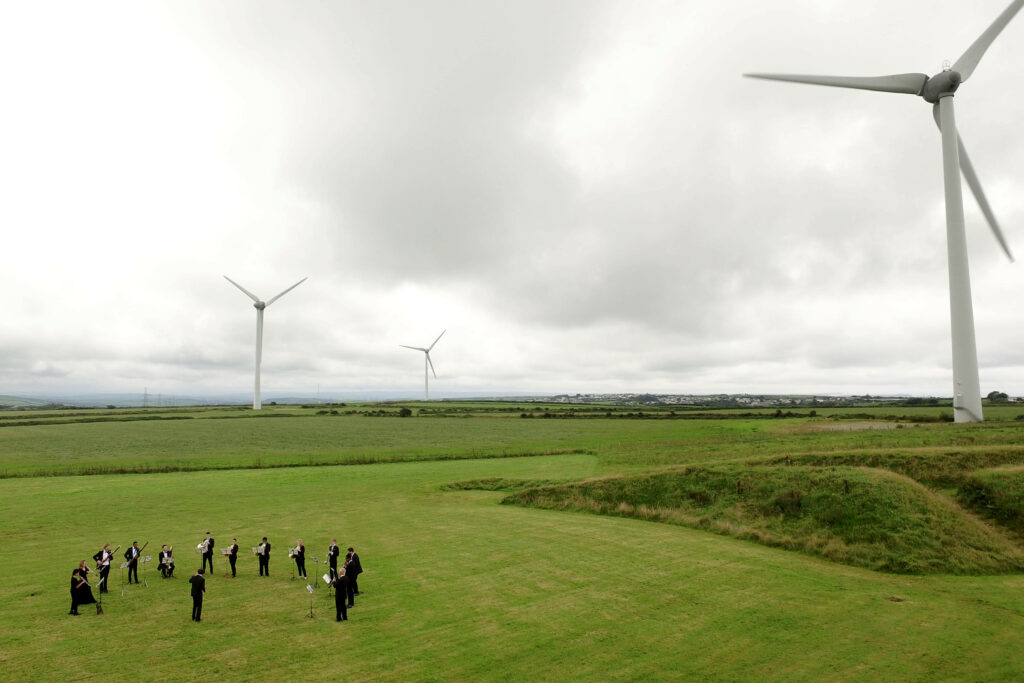 The Orchestra for the Earth performs by wind turbines at Delabole wind farm. Image: Emily Whitfield-Wicks.