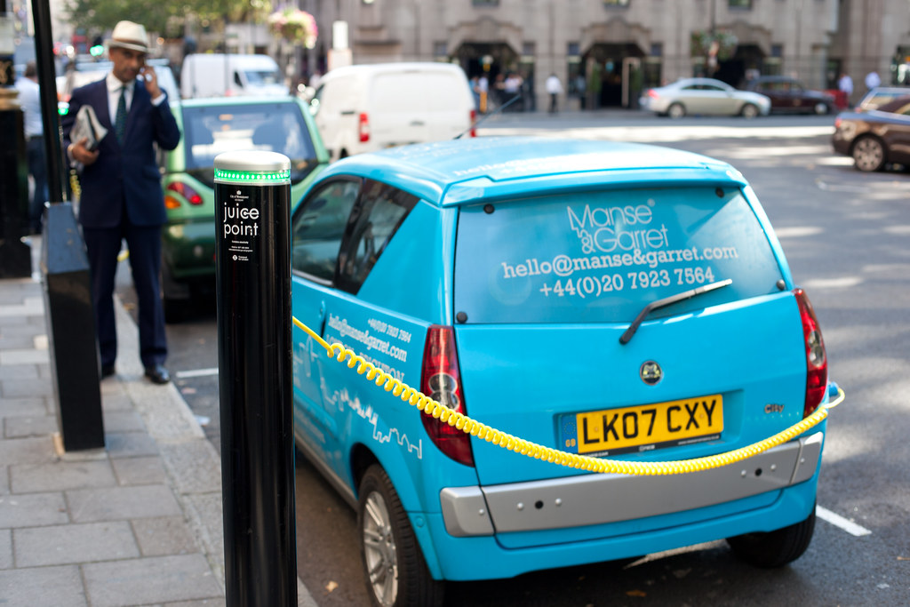 Recharging station for electric cars in London's Berkeley Square. For me, the bonus of the photo is the dapper gentleman with his newspaper speaking on the phone.