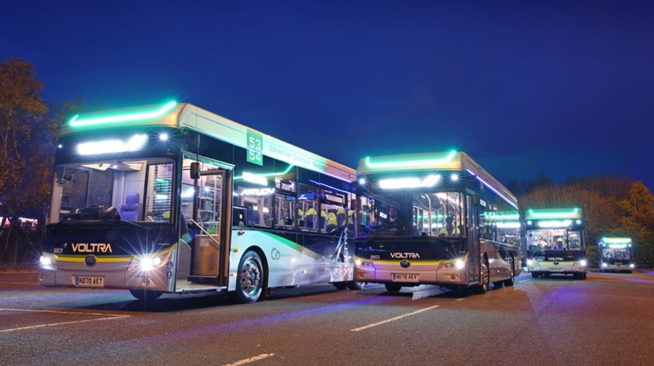 An image of two buses in the dark with lights on