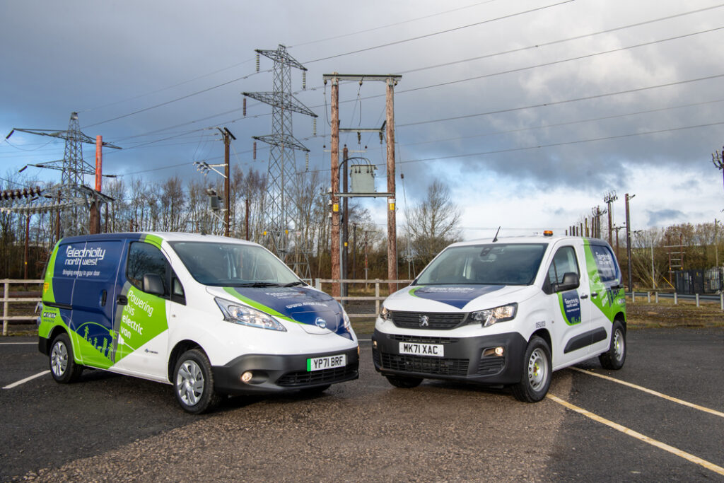 A pair of vans from the brand Electricity North West parked in front of electricity pylons.