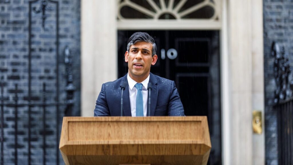 Rishi Sunak stands at a lectern in front of 10 Downing Street, drenched in rain