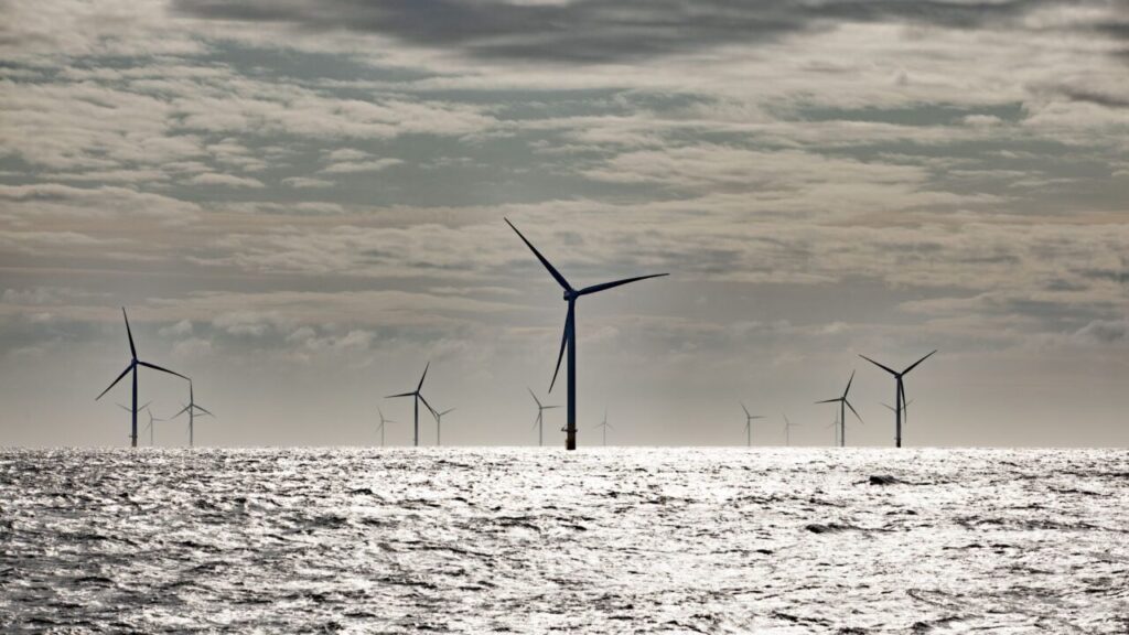 A collection of wind turbines sitting in a grey sea under a cloudy sky