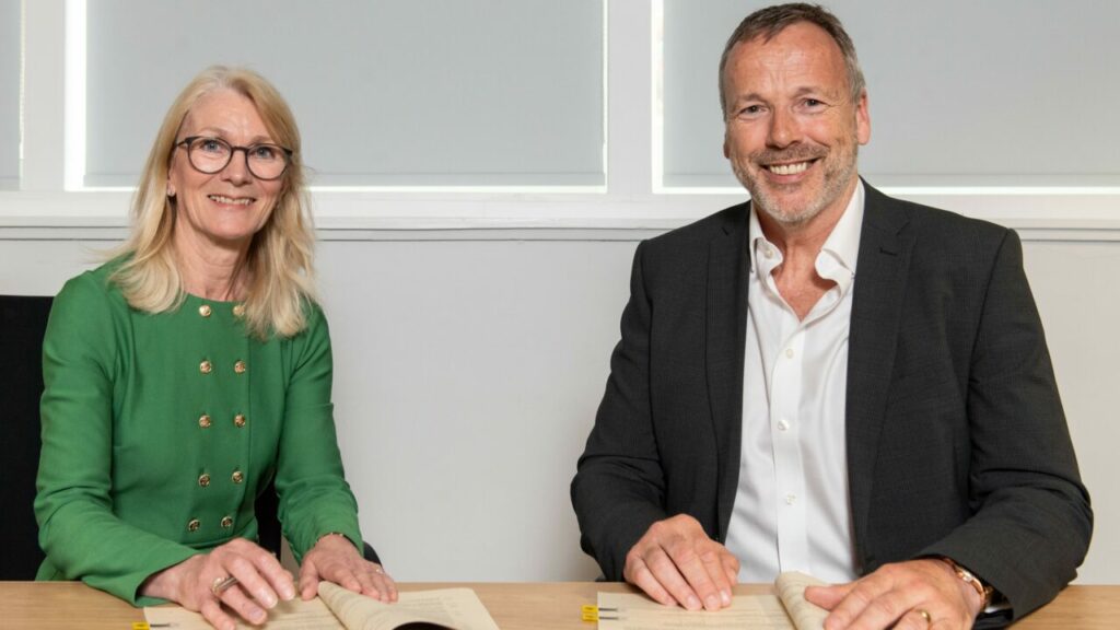 A woman and a man sit next to each other in business wear