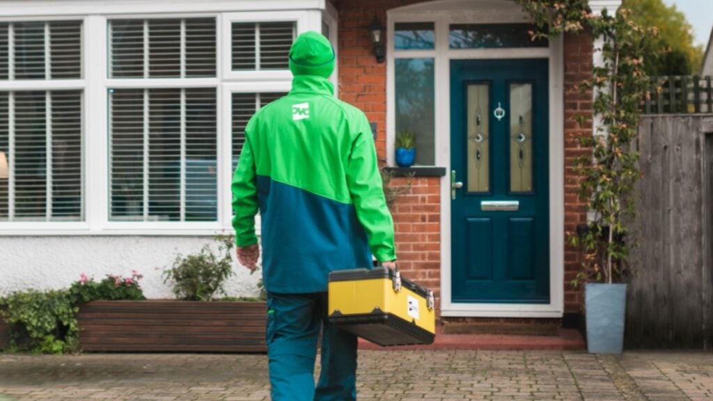 A person in an Ovo Energy uniform walks towards a house.
