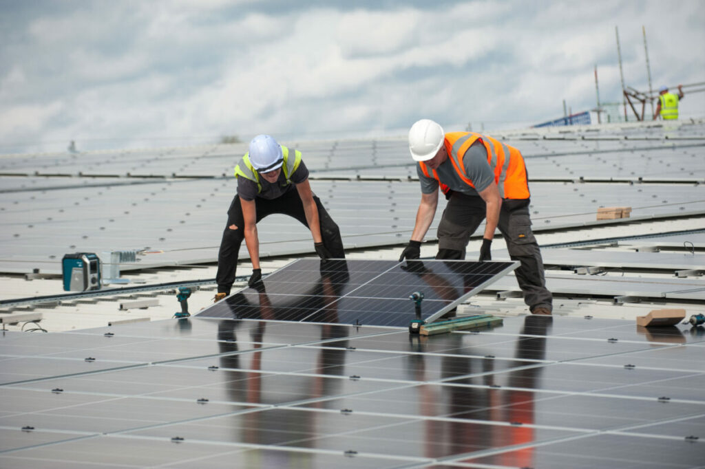 Workers install solar panels at a community energy site