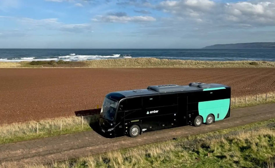 A bus branded with the Ember logo drives near a beach