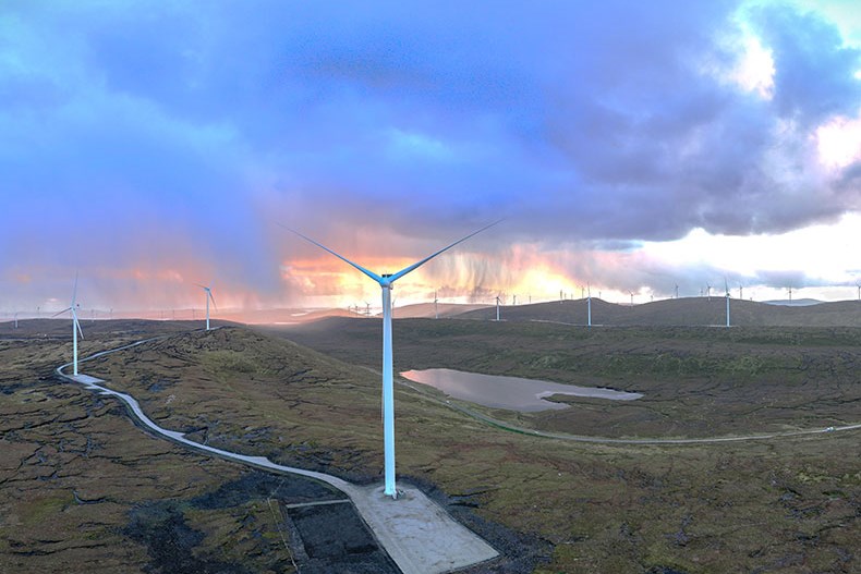 Image of a wind turbine with sun setting in the background.
