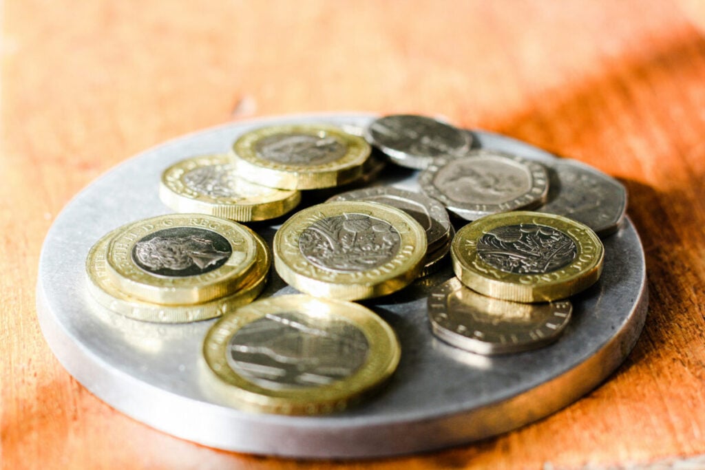 British coins of various denominations in a dish