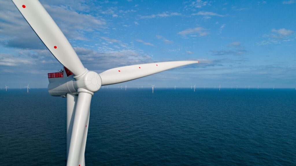 A wind turbine in front of a blue sea
