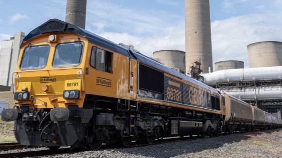 A freight train in front of a power station