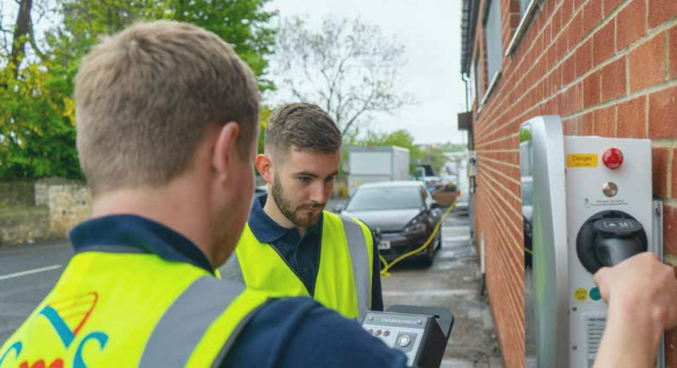Two white men install an EV charger on a wall