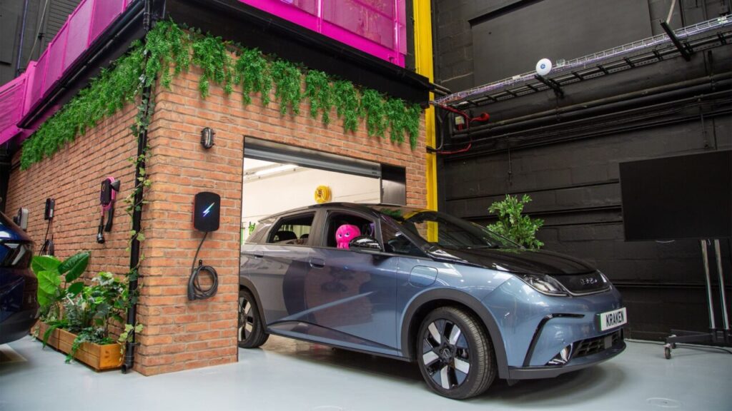 A car with a toy octopus in the window sits in a garage next to an EV charger in the Kraken Tech Centre