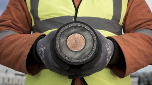 a cross section of an electricity interconnector cable, held by a person in a high vis vest