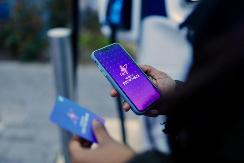 A person looks to their phone and card, both with the Octopus Electroverse logo on