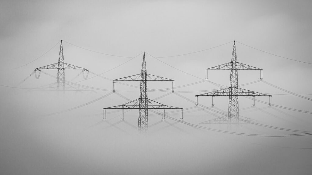 Three electricity pylons surrounded by hevy fog