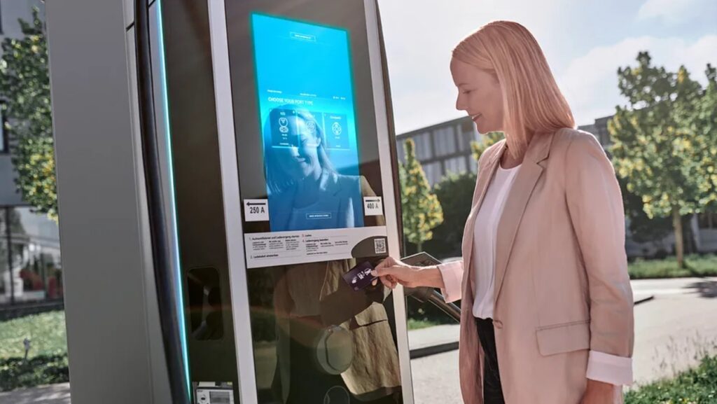 A woman smiles as she taps a card on an EV chargepoint