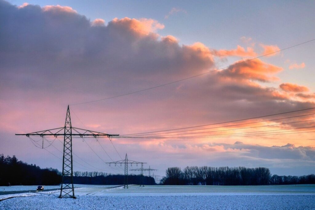 A pylon at sunrise in fields lightly dusted with snow