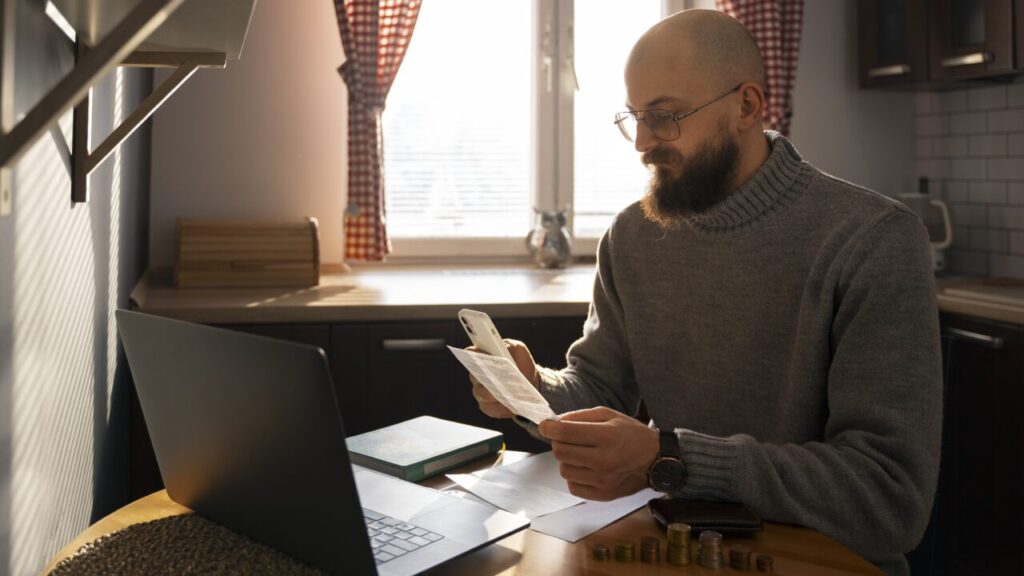 A man sat in front of his laptop looks at an energy bill and looks worried