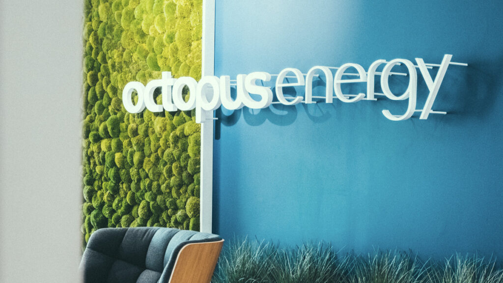A blue and green office wall with the octopus energy logo mounted on it