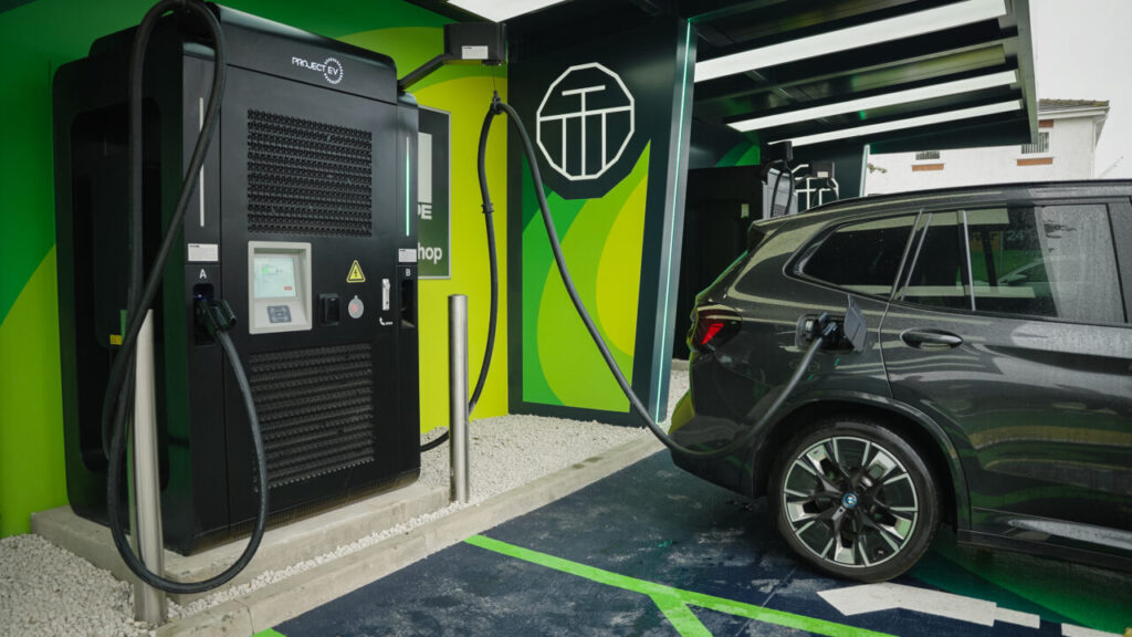 A lime green and black Ev charging station plugs into an electric car