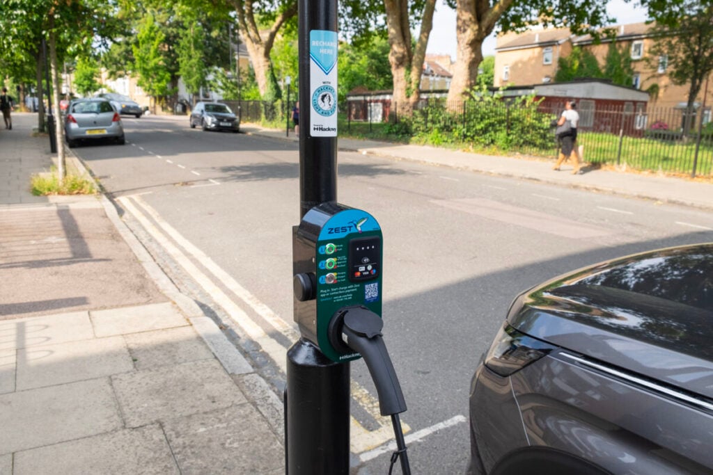 a zest ev charger on a lampost with an ev plugged into it