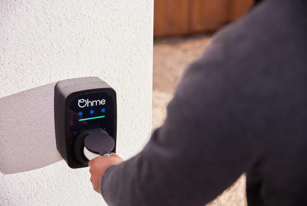 a hand operates an Ohme EV charger