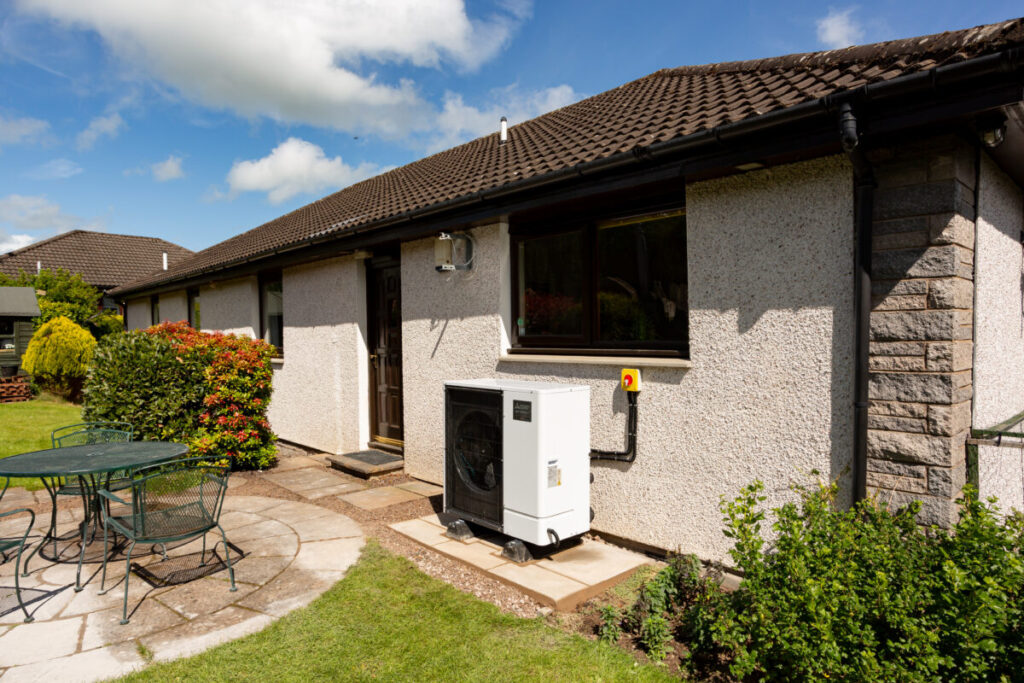 A bungalow with a heat pump installed outside