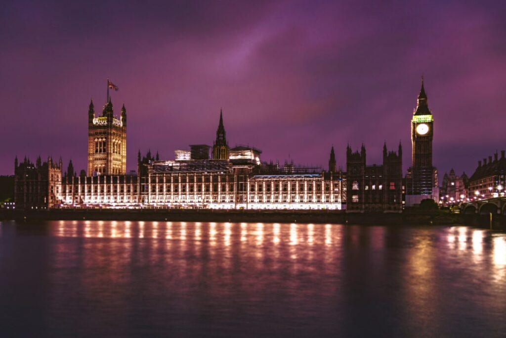 The houses of parliament lit up at night in front of a purple-tinged sky
