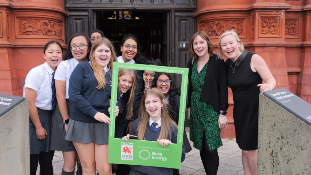a group of schoolchildren smile and hold a frame with the bute energy logo