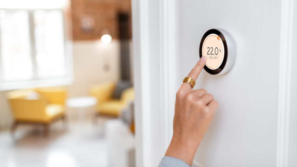a hand adjusts the temperature on a smart digital thermostat