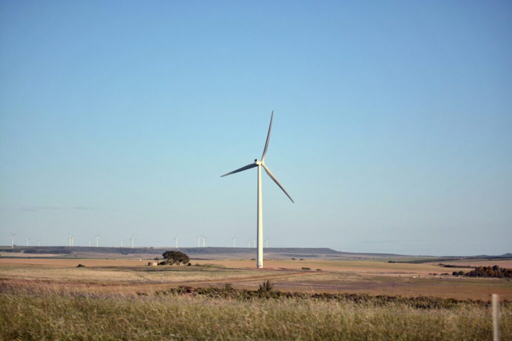 A single wind turbine on a hill underneath a blue sky