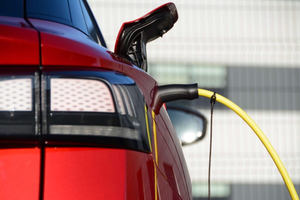 a red EV plugged into a charger