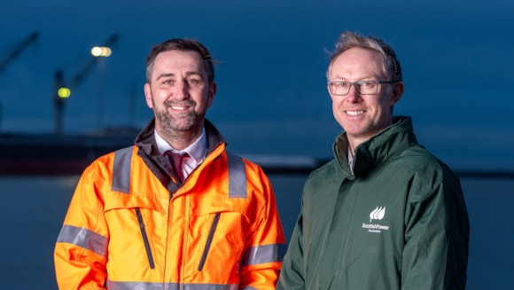 two men stand and smile at the camera