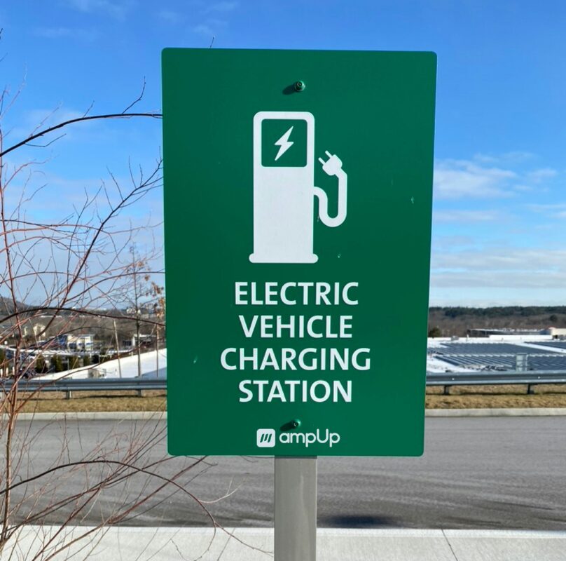 a green sign with an icon of an EV charger and white text reading Electric vehicle charging station