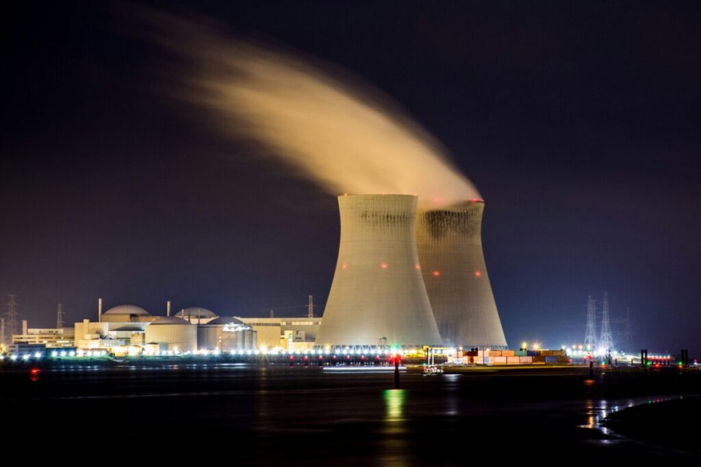 power plant towers eject clouds into the night sky