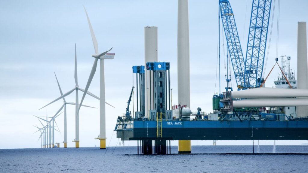 a platform in the ocean next to offshore wind turbines