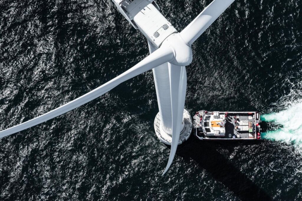 an offshore wind turbine from above with a boat next to it