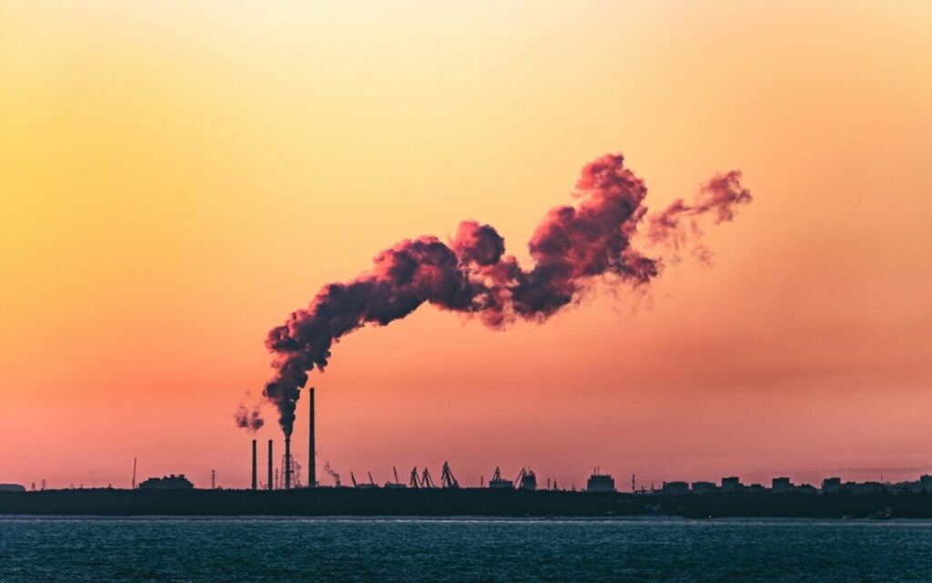 a smoke stack in the far distance at sunset