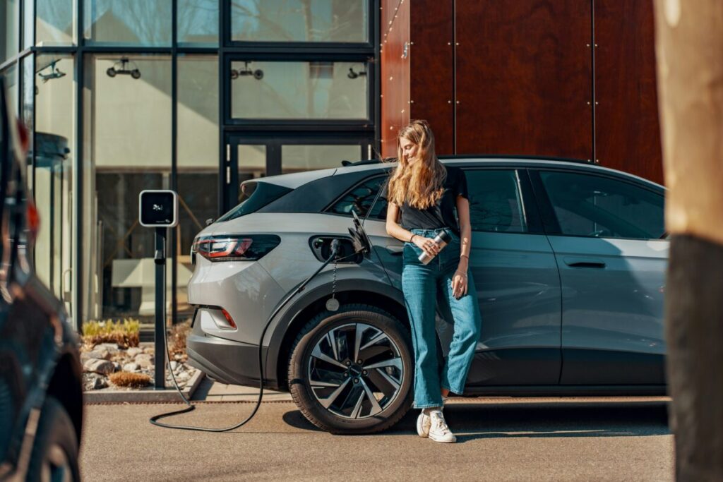 a woman stands by an EV on charge