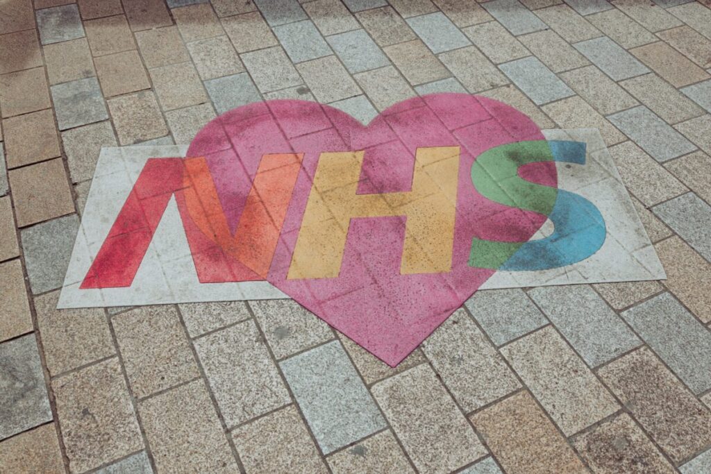 an NHS logo on the floor with a heart behind it and NHS written in rainbow letters