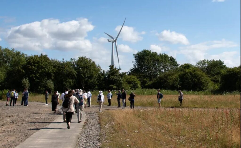a group of people gather with a wind turbine in the background