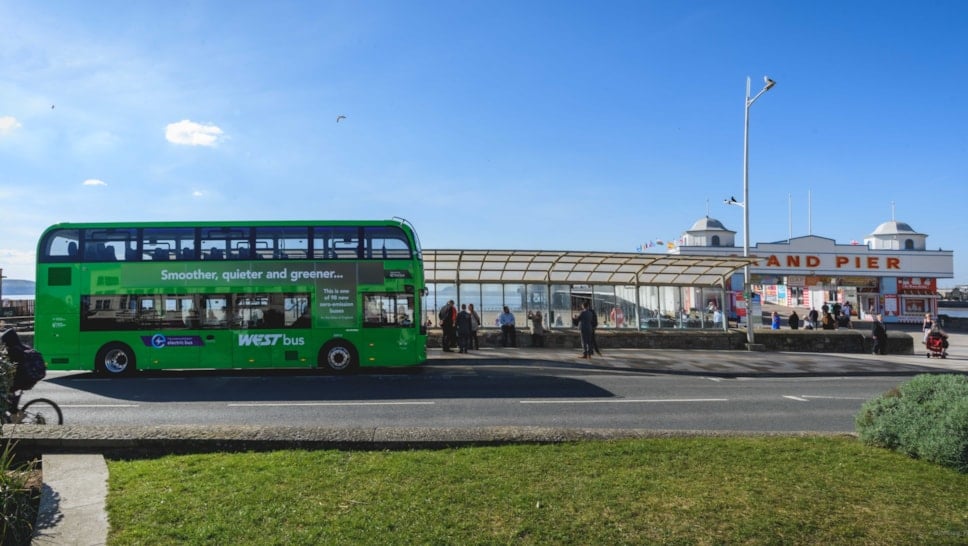 a green bus drives by the seafront