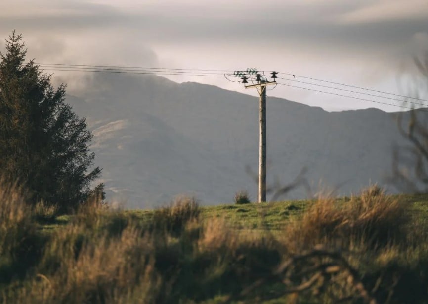 an electricity pole with rolling mountains behind