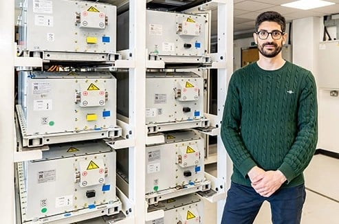 a man stands next to a rack of batteries