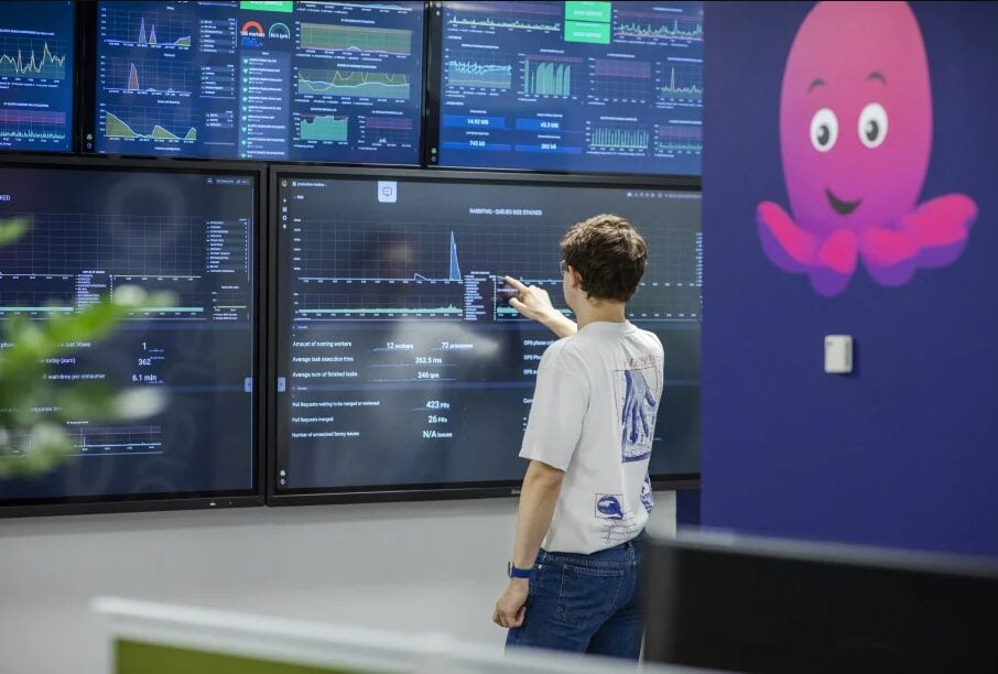 a person looks at screens with their back to the camera next to a large panel with the octopus energy logo on