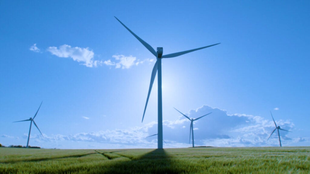 wind turbines in a green field under a blue sky