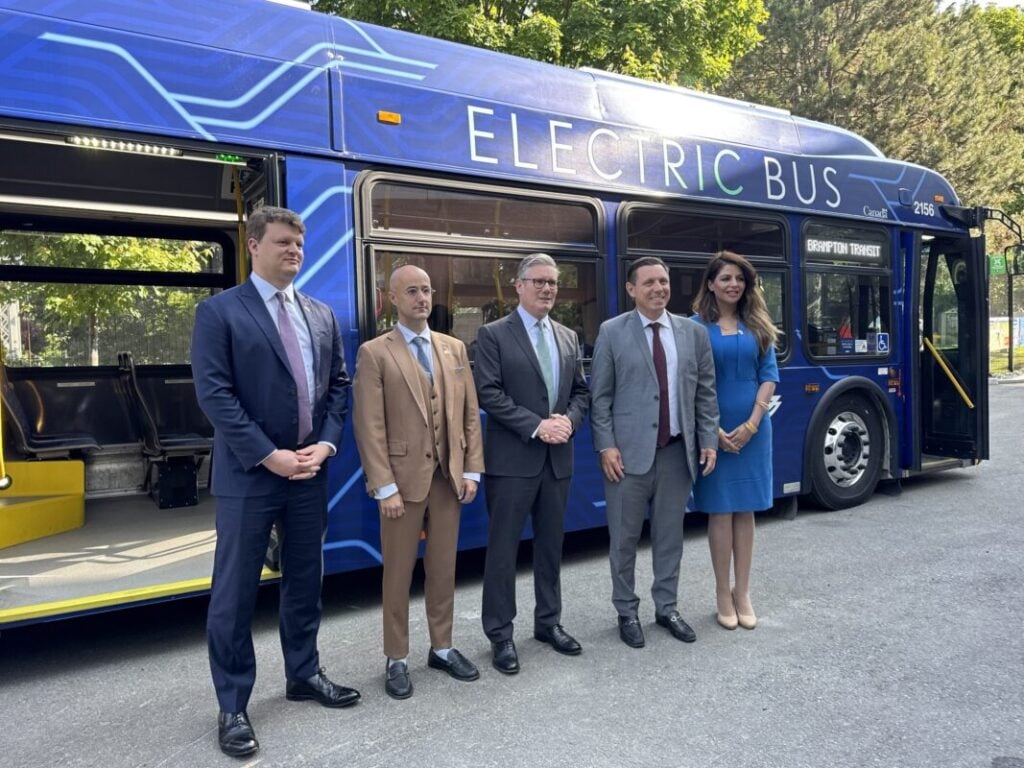 a group of people pose in front of a blue e-bus
