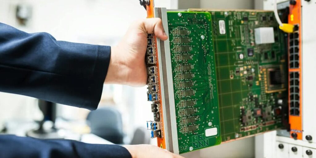 a pair of hands holds a large computer motherboard