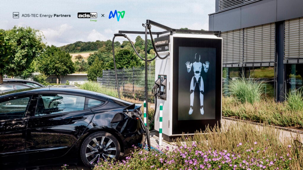 an ev charger with a large digital screen showing a robot, into which an EV is plugged